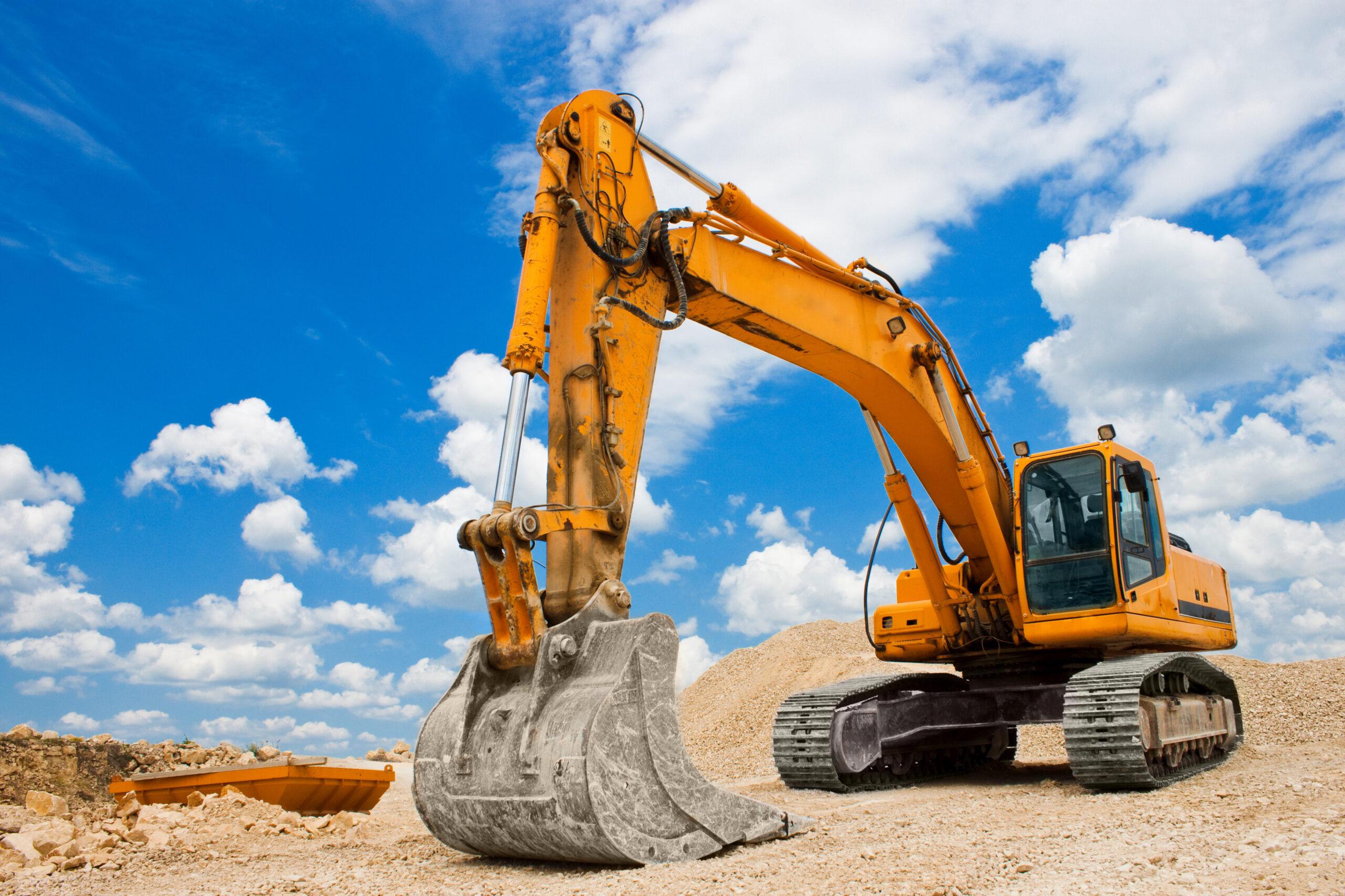 Yellow,Excavator,On,A,Construction,Site,Against,Blue,Sky